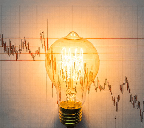 Lit light bulb over a market price graph